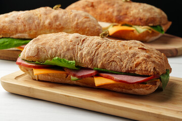 Chiabatta sandwich with ham and cheese on wooden board