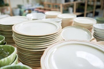 Exploring Handcrafted ceramic tableware and utensils in a craft shop. Indoors design. Stacked bowls and dishes of a stylish shop.