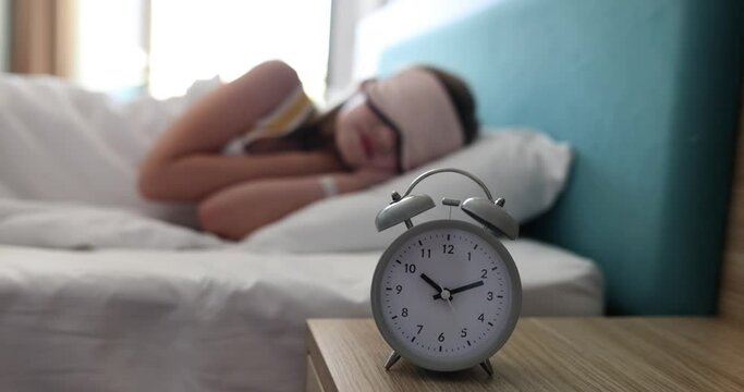 Child teenager lying in bed in blanket calm confident alarm clock will ring at ten o'clock in morning. Sleeping with a sleep mask
