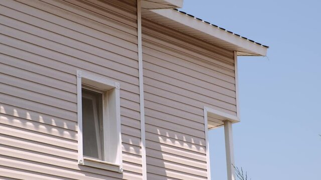 The facade of the new house clad with siding, with windows, against the blue sky.