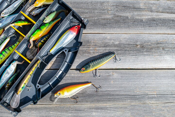 A fishing tackle box, complete with lures and fishing gear on a wooden background on top. A set of...