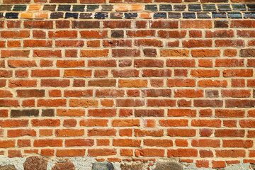 Texture of an old and damaged orange brick wall with natural stones and ceramic tile as an architectural background