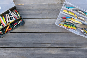 A fishing tackle box, complete with lures and fishing gear on a wooden background on top. A set of fishing lures for spinning fishing.