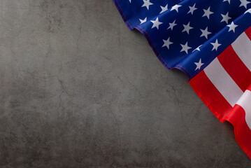 Patriotic holiday celebration: top-down photo featuring the American flag on a grunge textured grey concrete background. Ample copy-space for advertisements or text placement during the public holiday