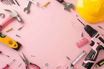 Recognizing the impact of female workers on Labor Day. Above view photograph featuring a pink backdrop, helmet and building tools, offering copyspace for adverts or text