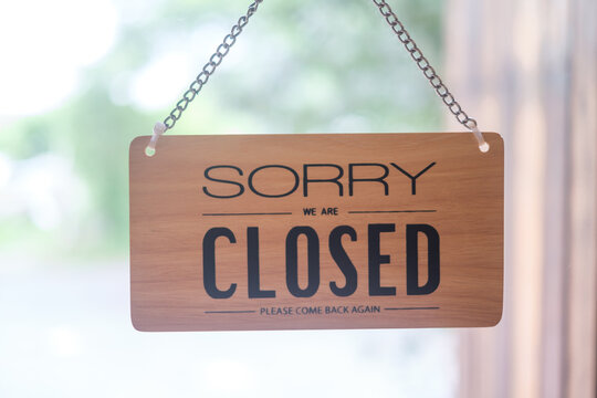 Sorry We Are Closed Wooden Board Hanging In Front Of Glass Door Window Of Store Cafe Shop.