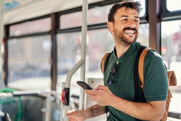 A happy commuter with a phone is riding a public transport.