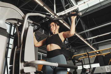 Fototapeta na wymiar Sporty woman workout pulling up on bar in fitness gym. Lady bodybuilder exercising pulls herself in sports center, weight working out. Healthy lifestyle and sport training concept. Copy ad text space