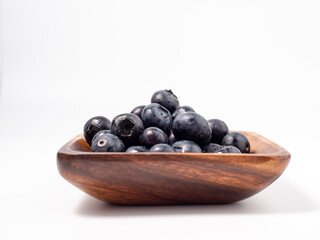 Ripe blueberries in a wooden bowl on a light background. blueberries close up