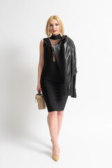 Woman in a black elegant dress with a handbag and a casual jacket in her hands