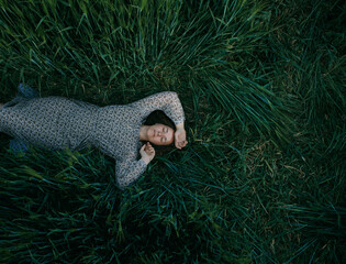 Young girl lying on green wheat field
