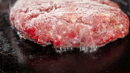 Closeup of steam flowing from cooking burger patty on electric grill. Cooking at home, kitchen appliance, healthy nutrition, hamburger ingredients.
