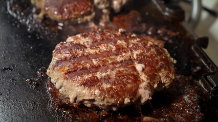 Closeup of cooking beef burgers on electric grill at home. Cooking at home, kitchen appliance, healthy nutrition, hamburger ingredients.