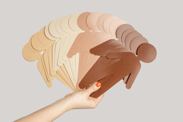 Closeup of woman hand showing paper symbols of multicultural people, racism, partnership. Indoor...