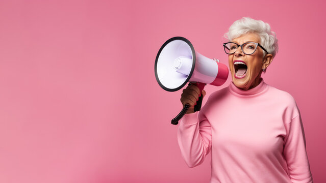Passionate elderly woman with a megaphone; pink background with empty space for text  - Powered by Adobe