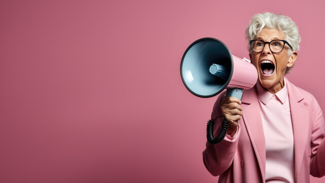 Passionate elderly woman with a megaphone; pink background with empty space for text 