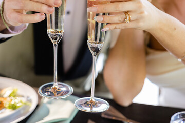 torsos of bride and groom at outdoor summer wedding holding champagne glasses