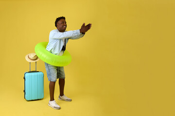 Young African athlete-swimmer goes on vacation with a lifebuoy, demonstrates the pose of a diver. A cheerful black man in clothes is preparing to jump into an unforgettable journey