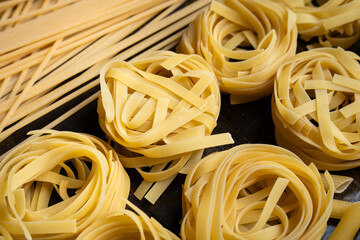 Pasta shapes, spaghetti and tagliatelle, italian cuisine ingredients on a wooden background