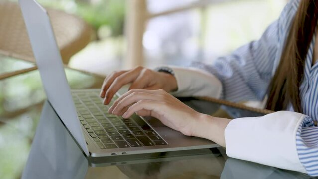 Close-up two slender hands an Asian woman, placed on keyboard on laptop computer, used keyboard fluently, quickly typed out tasks that needed be solved, in order stay on vacation.