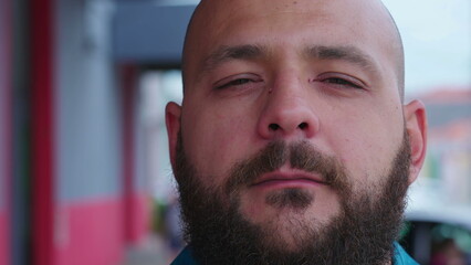 Obraz premium Portrait of a stern serious casual bold man with beard tight close-up face standing in street