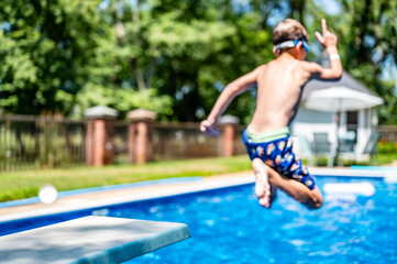 Selective focus on a swimming board as a young boy jumps into a pool. 