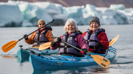 Obraz premium Three elderly attractive women with a happy expression on face kayaking in the Arctic, icebergs in the background