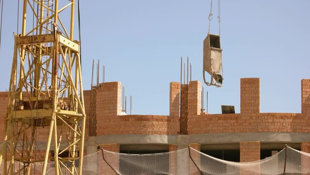 Yellow crane moving over the construction site. Clear blue sky ibb the background.