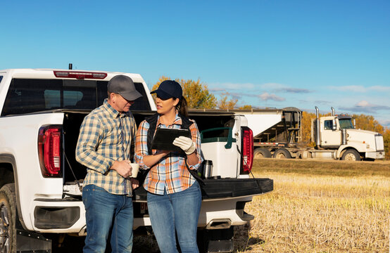 Farm couple uses tablet to monitor fall canola harvest while taking a coffee break, Alberta, Canada