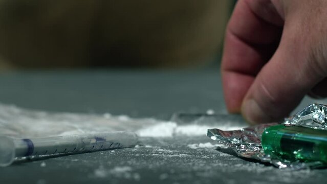 Drug addict preparing lines of heroin for injection