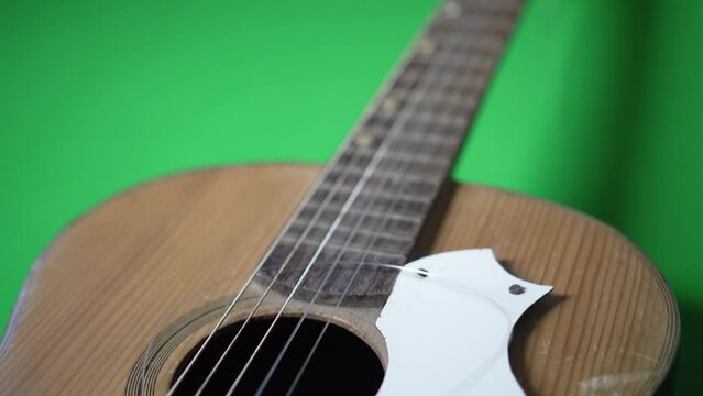 An ancient guitar with broken string on a green floor