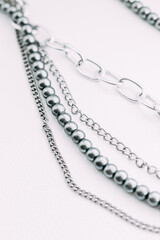 A necklace of gray beads with chain decorations on a white aesthetic background.