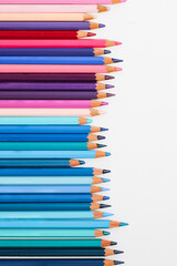 Multi-colored pencils lie on a white table, the violet range of colors