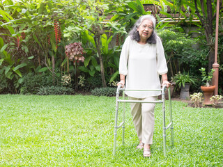 Asian senior holding a walker and walking in the park. healthy of elder woman.