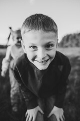 Child. Kids playing in mountains on autumn day. Daughter, son hugging in green grass in field at sunset. Happy children walking spending time together in spring nature. Closeup. Black and white photo