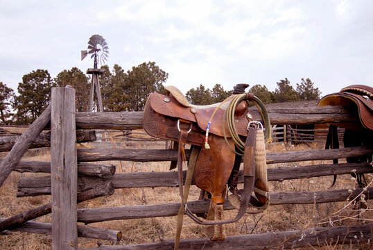 Saddles hanging on a wood rail fence, left by some ranchers in the Nebraska Sandhills; Halsey, Nebraska, United States of America