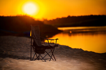 A Black chair on the beach during sunset