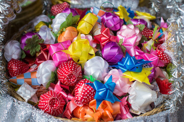 Fototapeta na wymiar Colorful ribbon flowers and coins folding with mulberry paper in the basket for giving alms in buddhist ordination ceremony. Thailand