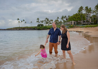 Family going for a walk on the beach, standing in the water along the surf on the shore at Kapalua Resort in West Maui; Maui, Hawaii, United States of America