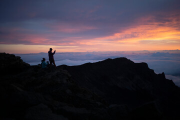 Family on a mountain top above the clouds at Haleakala watching the sunrise over the Pacific Coast; Haleakala National Park, Maui, Hawaii, United States of America
