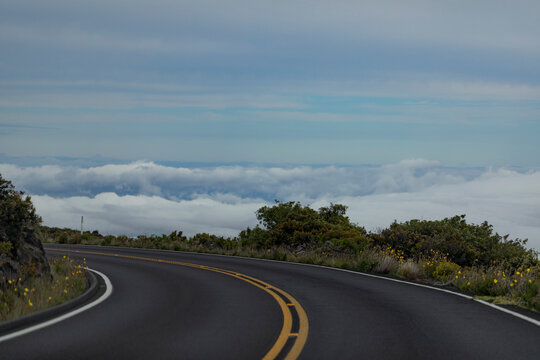 Close-up of a sharp turn in the paved highway with view from above the clouds on the mountainside on the Road down from Haleakala; Maui, Hawaii, United States of America