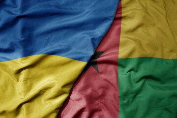 big waving national colorful flag of ukraine and national flag of guinea bissau .