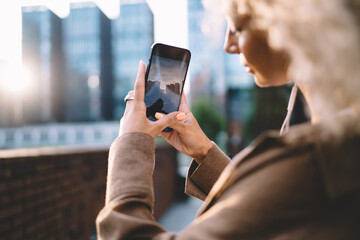 Focused woman taking picture of modern skyscrapers