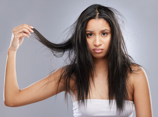 Hair, damage and portrait of woman in studio with worry for split ends, haircare crisis and weak strand. Beauty, hairdresser and face of upset female person with frizz problem on gray background