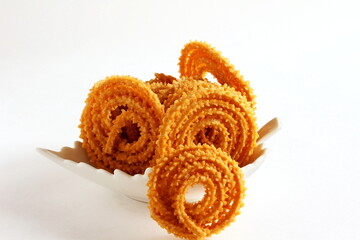 Indian Traditional homemade Tea Time Snack Chakli or chakri a spiral ring shaped crispy deep fried snack also  known in india as Chakali, Murukku, Muruku, Murkoo in bowl on white background