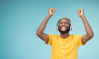 Music, dance and mockup with a black man in studio on a blue background wearing headphones. Radio, freedom and fun with a male dancing indoor alone while streaming an online audio playslist