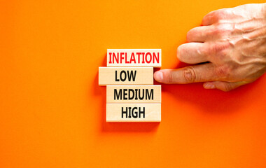 Low inflation symbol. Concept word Inflation low medium high on wooden block. Businessman hand. Beautiful orange table orange background. Business time to low inflation concept. Copy space.