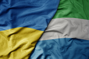 big waving national colorful flag of ukraine and national flag of sierra leone .