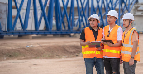 Obraz na płótnie Canvas Group of asian engineers discuss about work at site of building under construction,The contractor team discusses the design of the structure,Three workers are working outside.