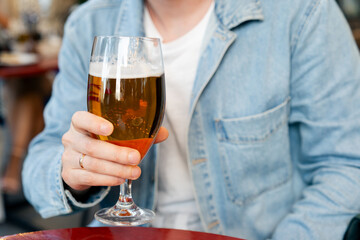 Man sitting at a restaurant table outside and drinking beer